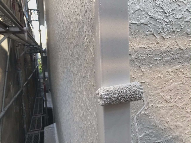 竪樋へのローラー塗装を行っている様子