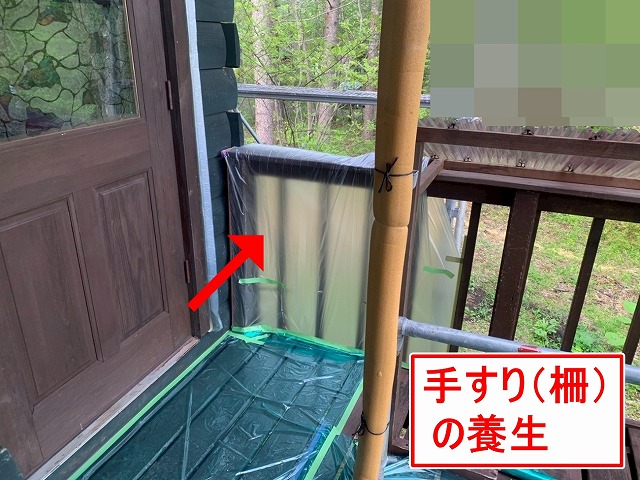 北杜市で別荘（ログハウス）の外壁塗装時に手すり（柵）に養生をかける様子
