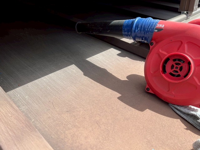 大月市で瓦棒葺きトタン屋根をケレン作業後、ブロワーで掃除する様子