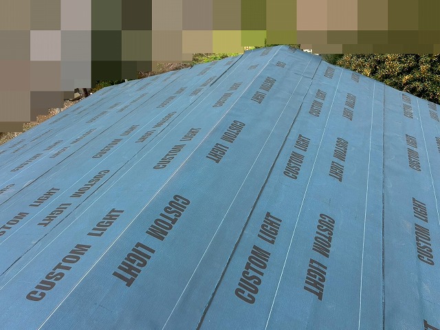 都留市で屋根に粘着層付の改質アスファルトルーフィングを設置する様子