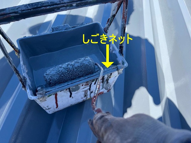 富士吉田市で屋根塗装の際しごきネットを使用してローラーに含ませる塗料を調整する様子