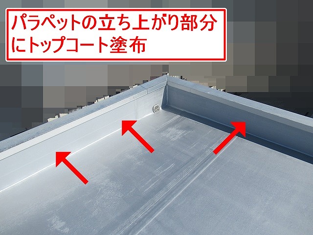 甲斐市で屋上のパラペットの立ち上がり部分にトップコート塗布を行う様子