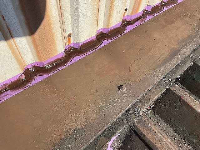 南部町で金属の折板屋根（波板屋根）にコーキング作業し、雨漏り修理する様子