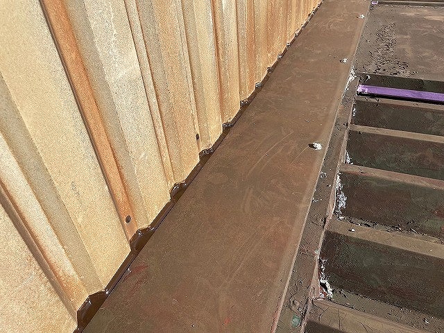 南部町で金属の折板屋根（波板屋根）にコーキング作業し、雨漏り修理する様子