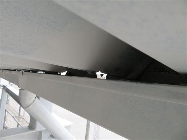 折板屋根の下部に設置された軒樋は、竪樋から遠ざかるにつれて雨水の滞留量が多くなっている異常な状態です