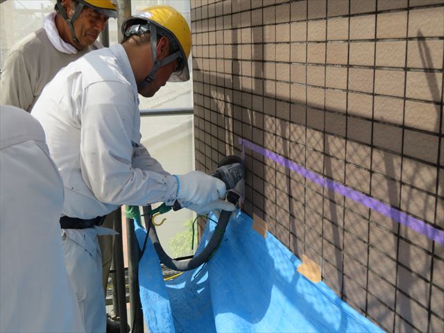 外壁タイルを斫る時は目地にサンダーで切れ目を入れていくが、切削粉塵がものすごく噴き出すので、集塵機でバキュームしながら進めて行く