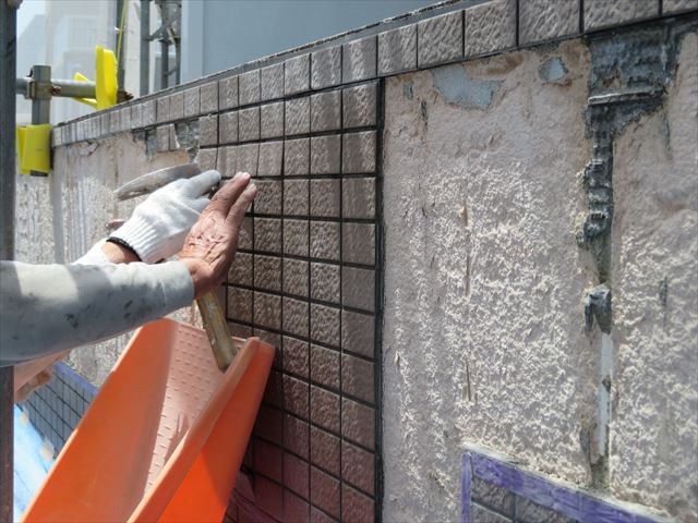 斫られた外壁タイルはすぐに何十キロの重さになるので、ブルーシートだけに頼らず、プラスチックの受け皿で受け止めていく