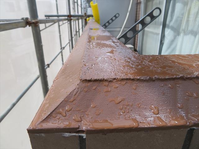 内壁の天端は水平のままですが、微弾性フィラー、プライマー、変成シリコンコーキングを用いた下地処理とともに完璧に雨水を弾いています。 ポリウレタン系コーキングで出来た傾斜には水滴が残っていますが、内壁の水平な天端との対比で、排水性の効果が分かります。