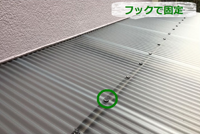 物置屋根のポリカ波板をフックで固定している様子