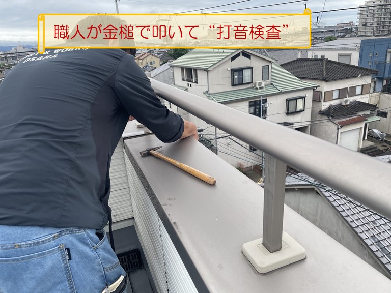熊取町で雨漏りがしているとのご相談職人がバルコニーの笠木を金槌で叩いて打音検査