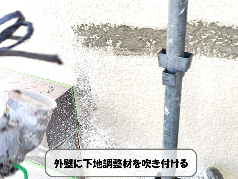 熊取町外壁に下地調整材を吹き付ける