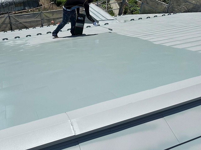 金属屋根塗装工事で3回塗りの中塗りを行う塗装職人