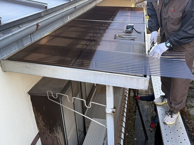ベランダ屋根のポリカ波板張り替え後に先端をハサミでカットしている様子