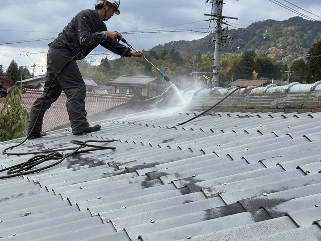 劣化したスレート瓦への高圧洗浄を行う屋根職人
