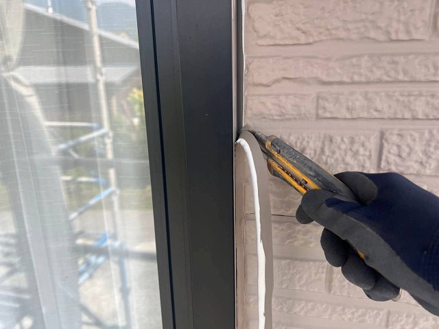 サッシまわりの劣化したコーキングをカッターで取り除いている様子