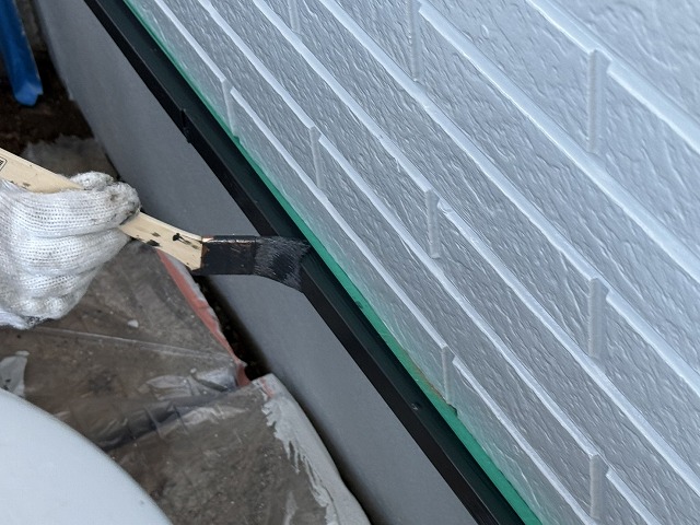 住宅外壁塗装工事の基礎水切りへのハケ塗りの様子