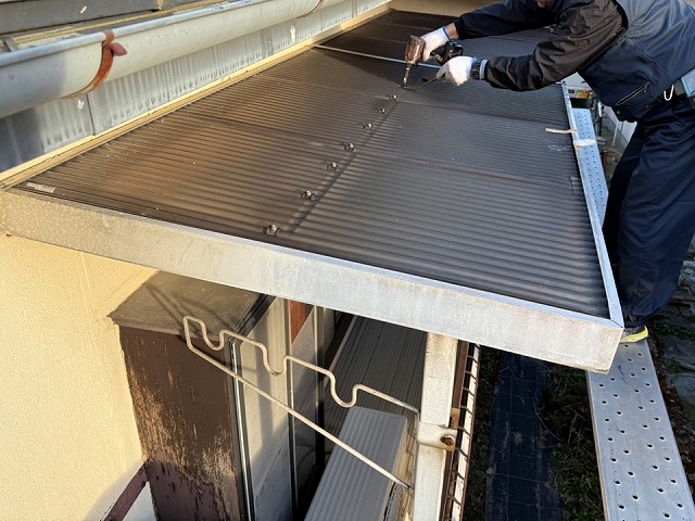 ポリカ屋根張り替え工事で既存ベランダ屋根の留め具を取り外している様子