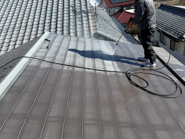 金属屋根に対する高圧洗浄で劣化した塗膜が取り除かれていく様子