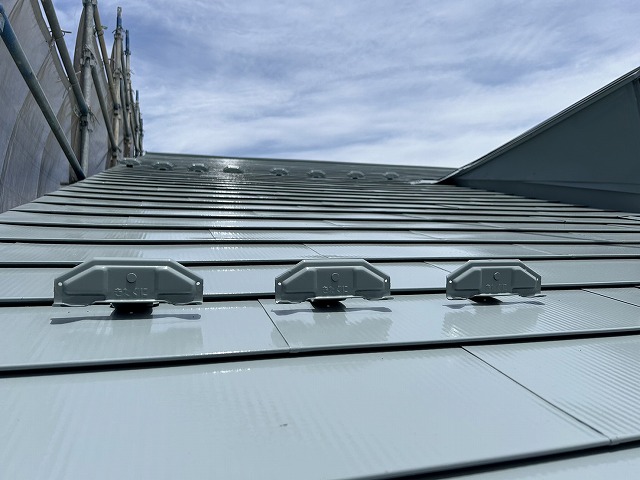 金属屋根塗装工事の雪止め金具への上塗り施工状況