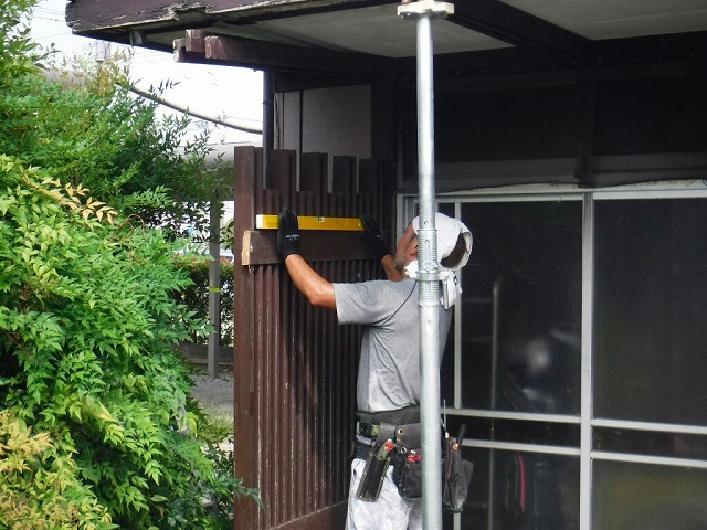 柱から切り離した目隠しの縦格子を水平器を使って元に戻しているところ