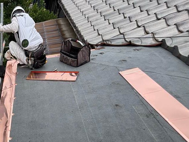 須恵町で屋根を撤去後防水シートを施工中の職人