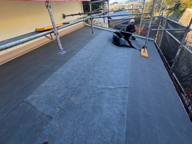 福岡市西区のカバー工事で防水シートの敷設作業中