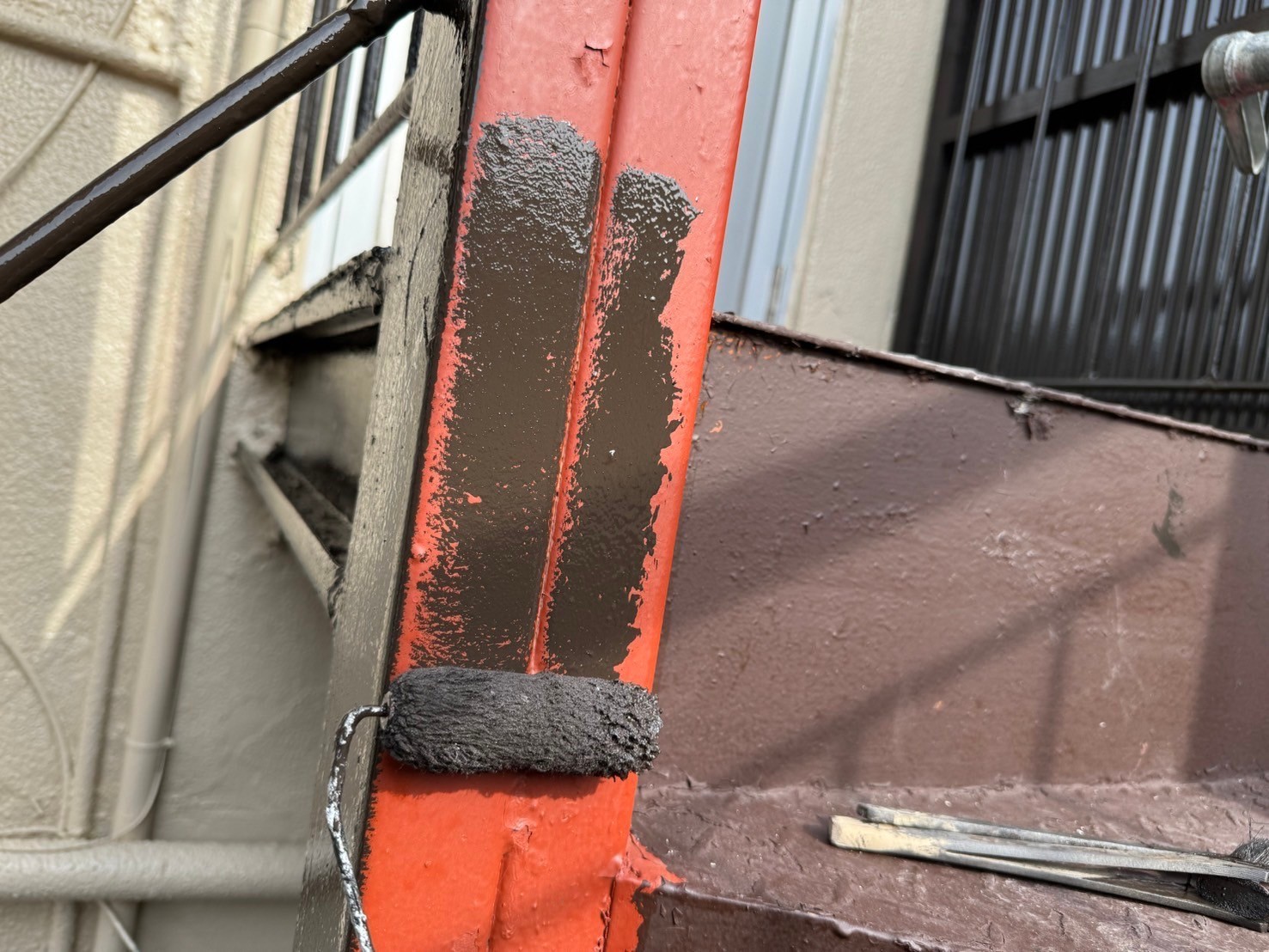 桑名市の長屋店舗の鉄骨階段塗装、二回目の柱塗装、中塗り作業風景