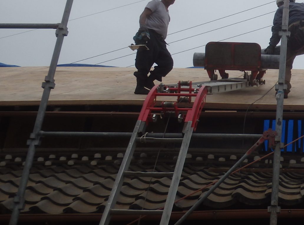 屋根の上に材料を送るハシゴ