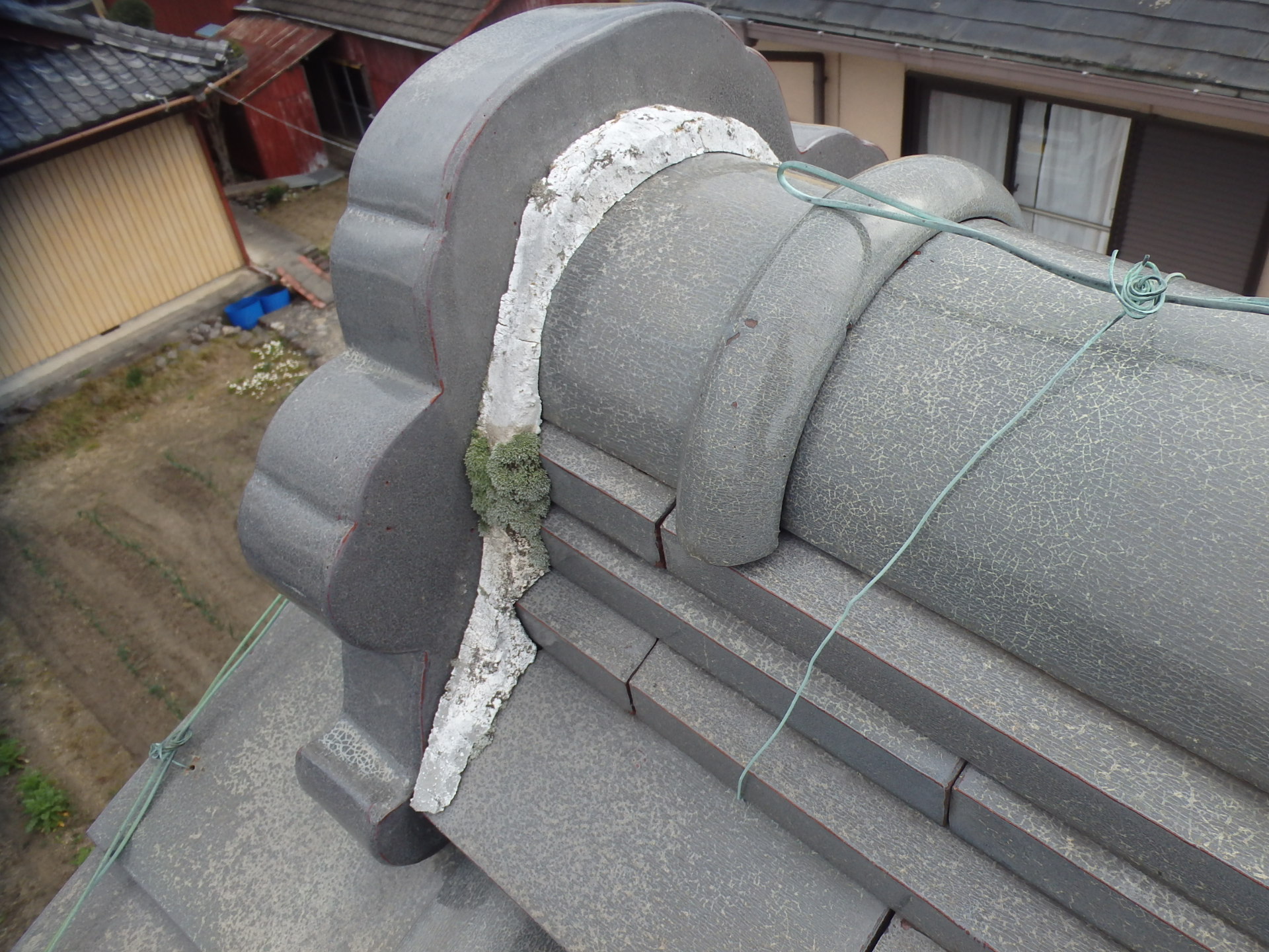 棟瓦の端部鬼瓦の漆喰劣化でコケが生えた状況