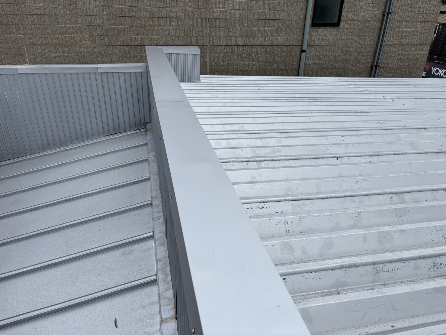 笠木の劣化により雨漏りが発生していた倉庫屋上に、新たに大きめの笠木を被せて雨漏り修理を実施した様子