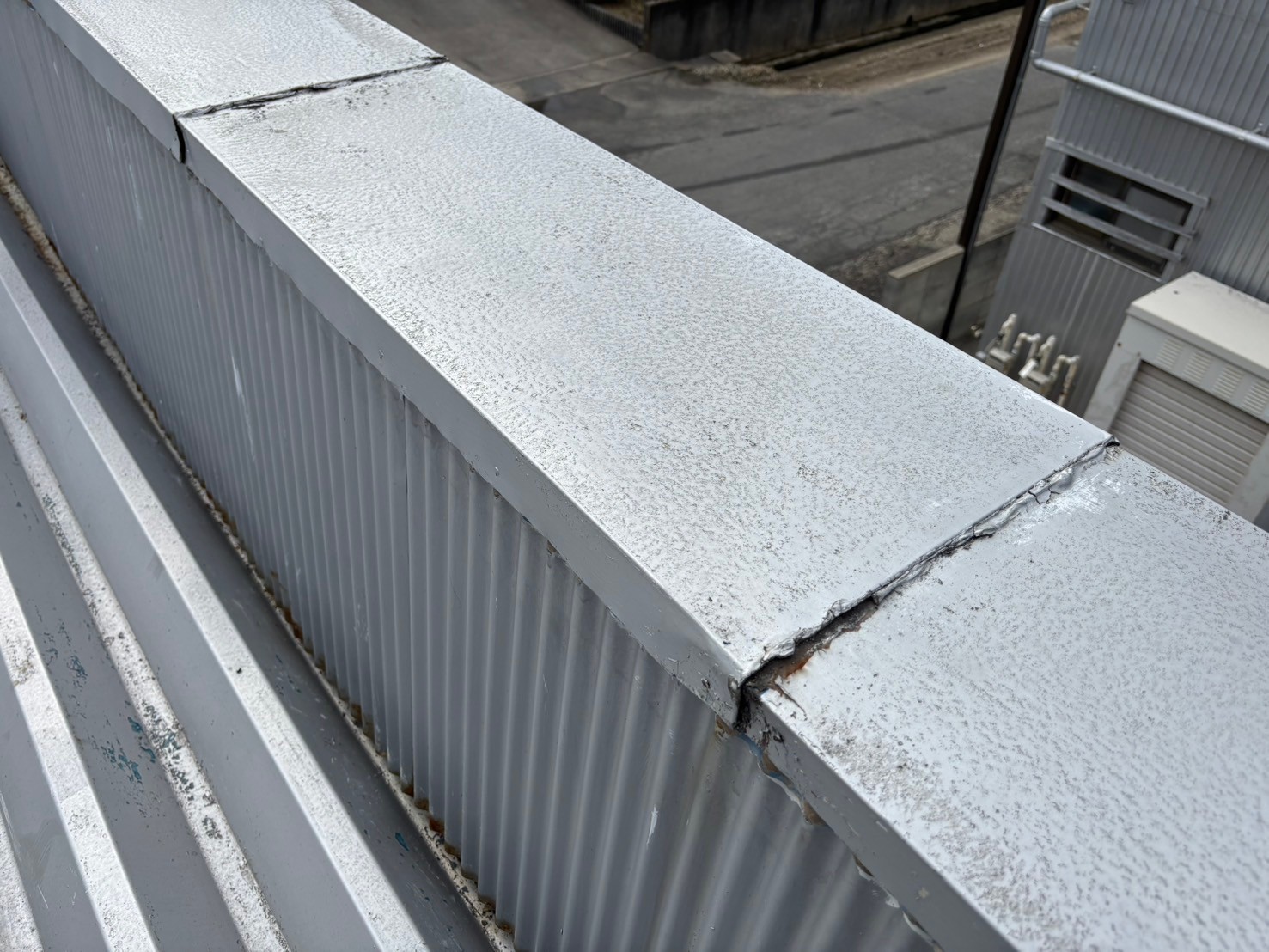 笠木の劣化により雨漏りが発生していた倉庫屋上に、新たに大きめの笠木を被せて雨漏り修理を実施した様子