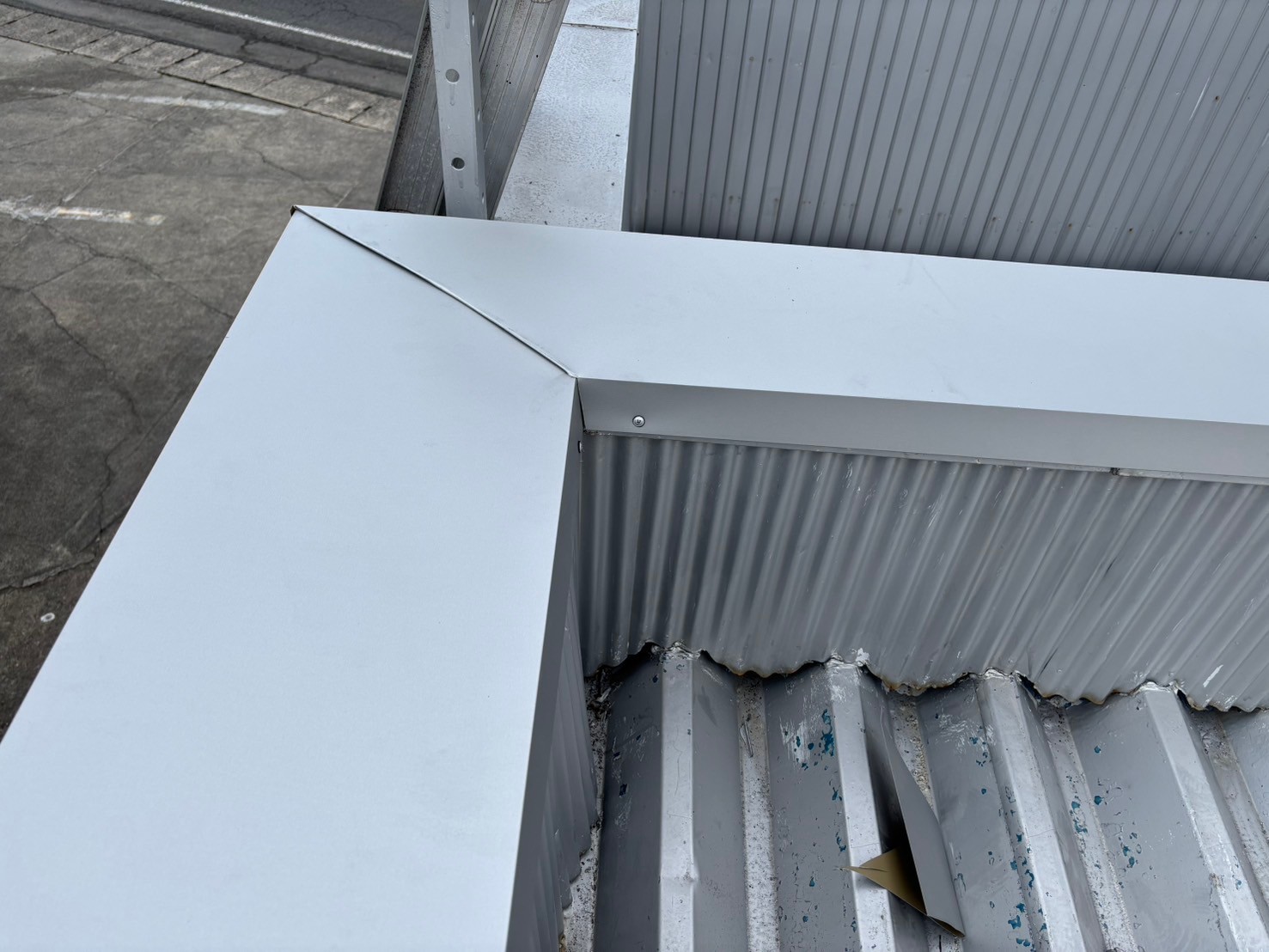 笠木の劣化により雨漏りが発生していた倉庫屋上に、新たに大きめの笠木を被せて雨漏り修理を実施した様子