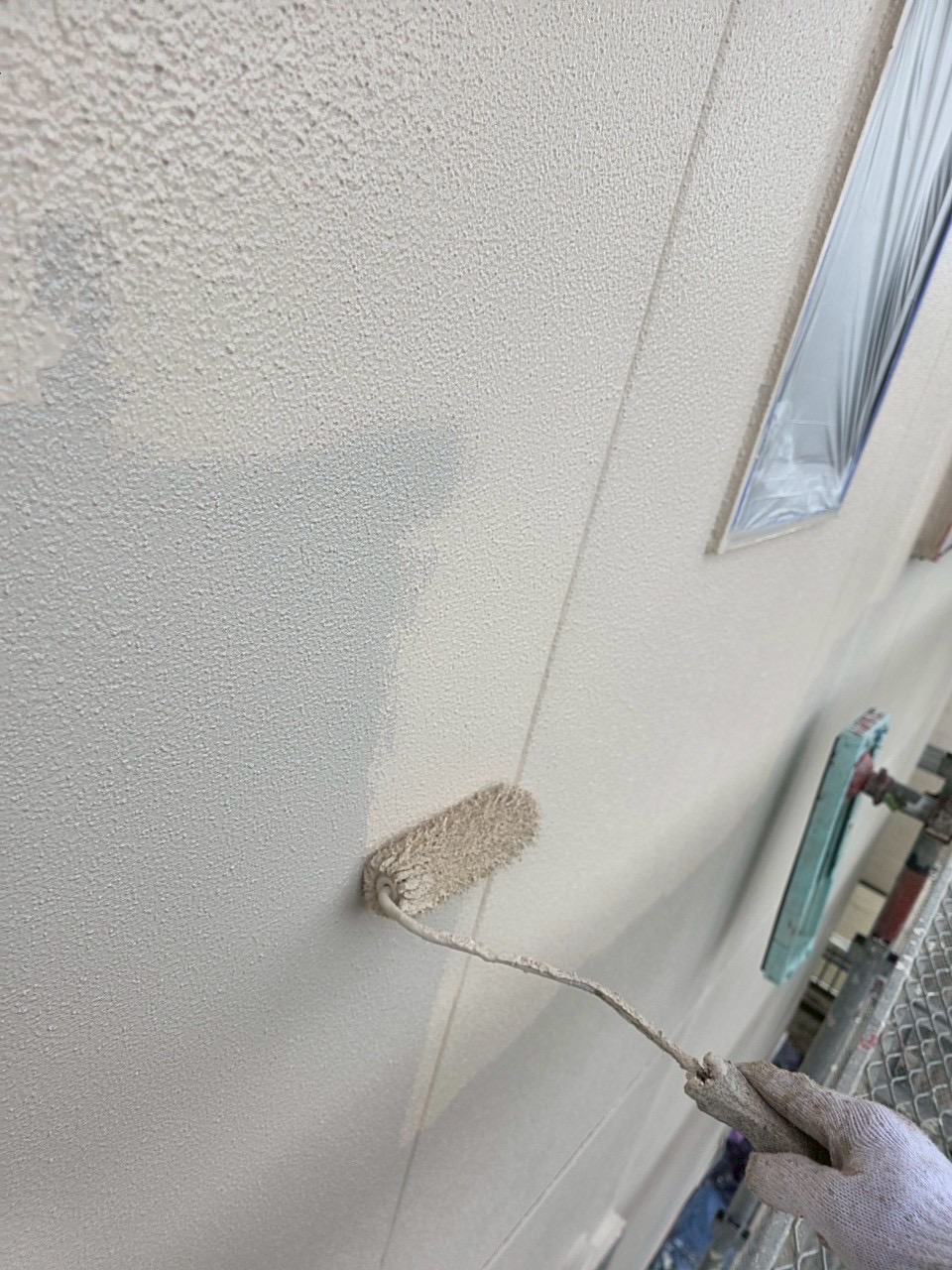 施工現場で外壁に塗装を行う職人の写真四日市市