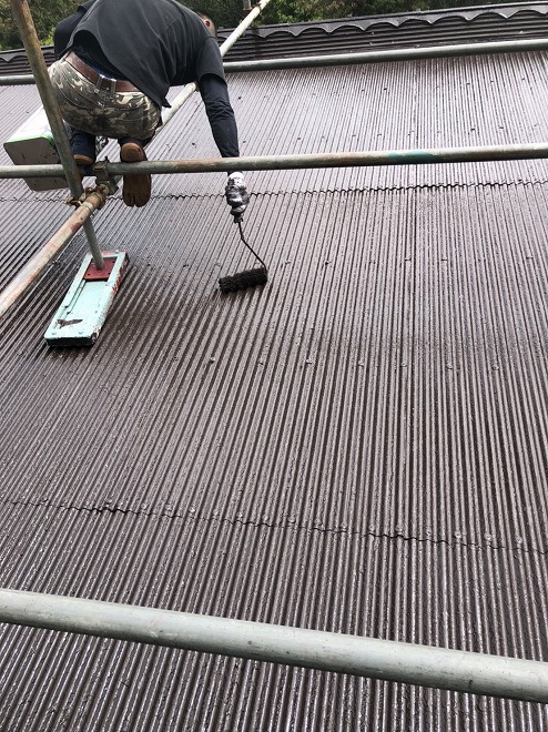 トタン屋根にローラによる塗装作業