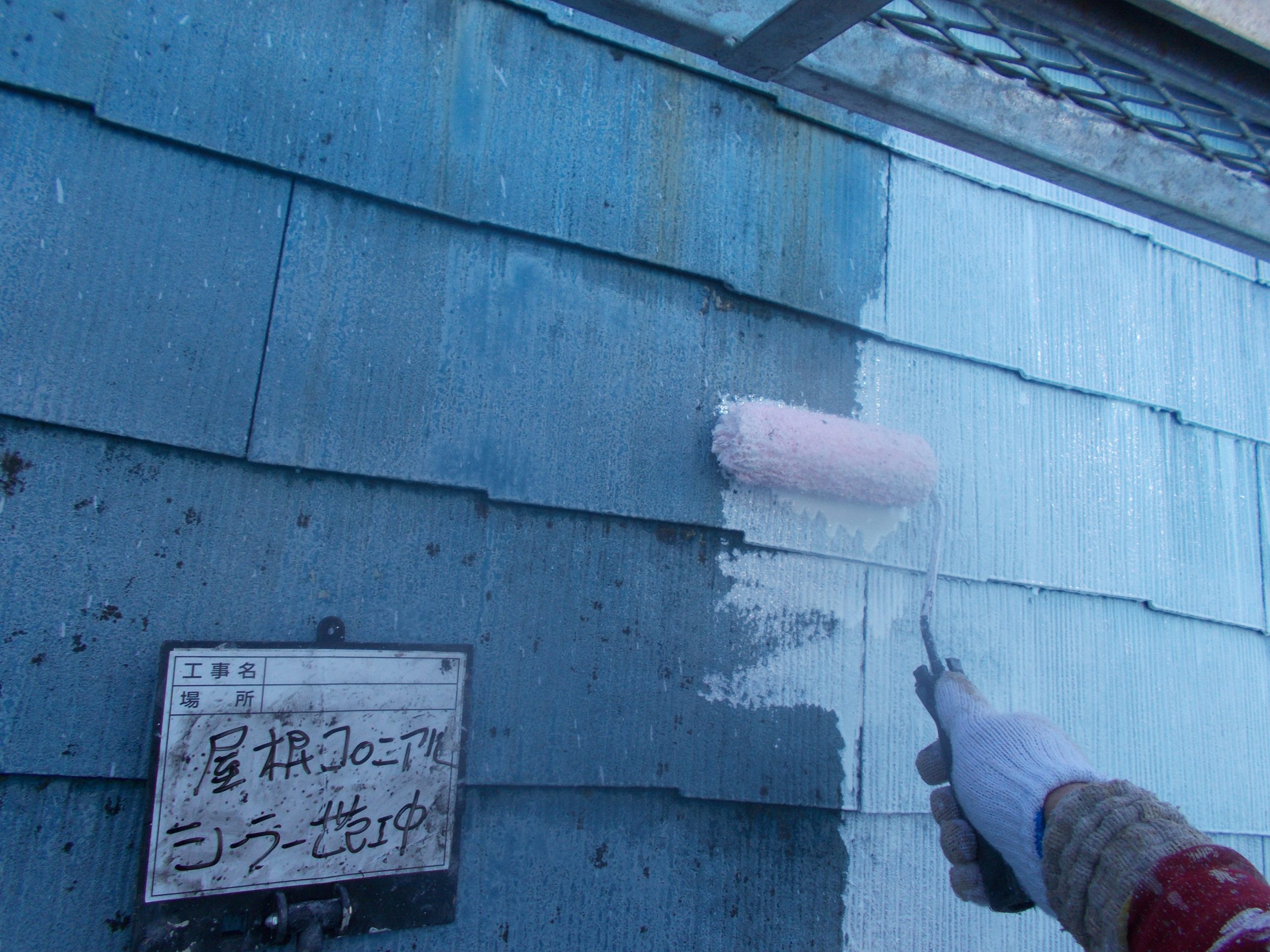 色褪せたコロニアル屋根に白い塗料でシーラー塗装中