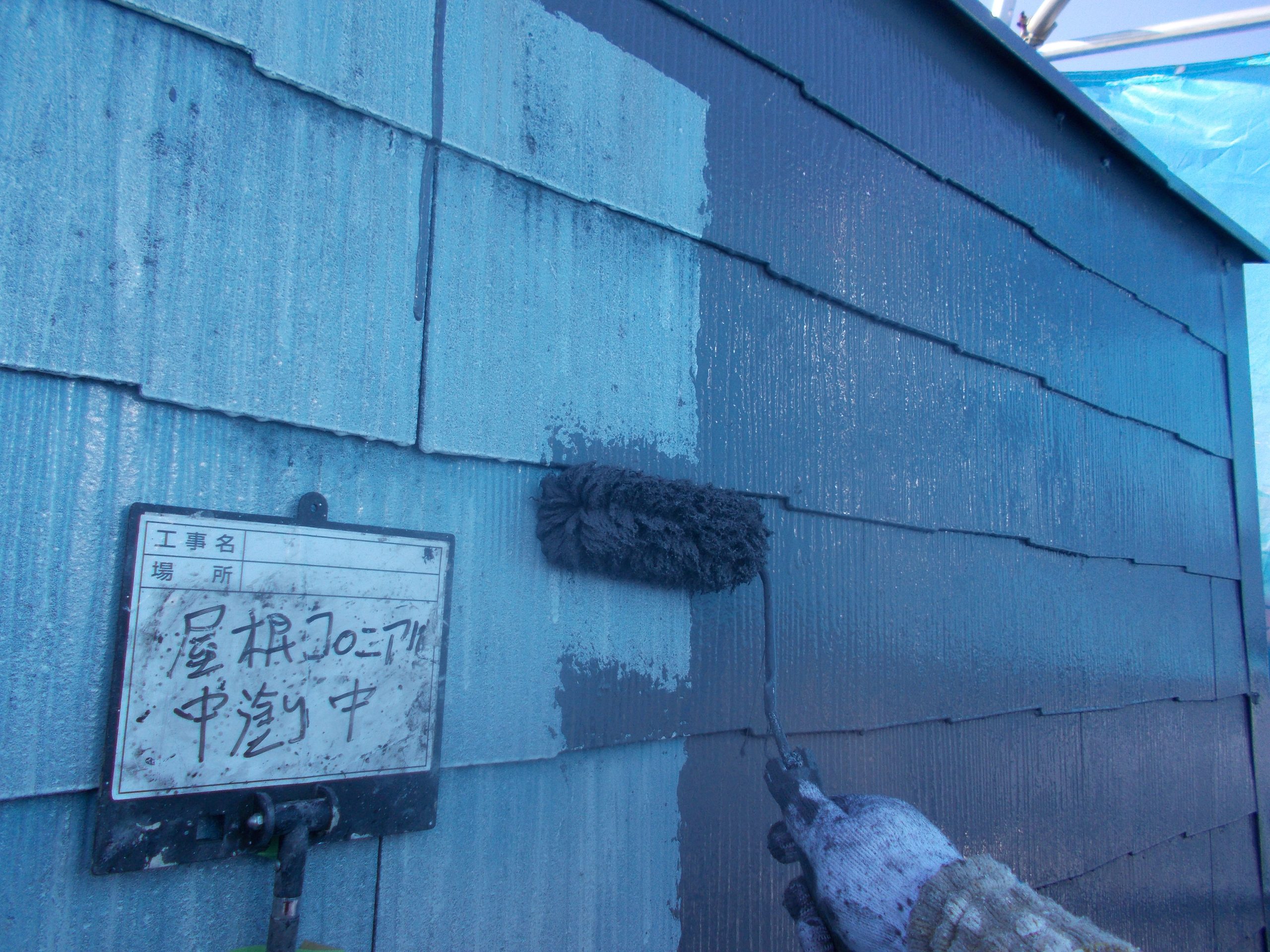 黒色の塗料で中塗り中のコロニアル屋根