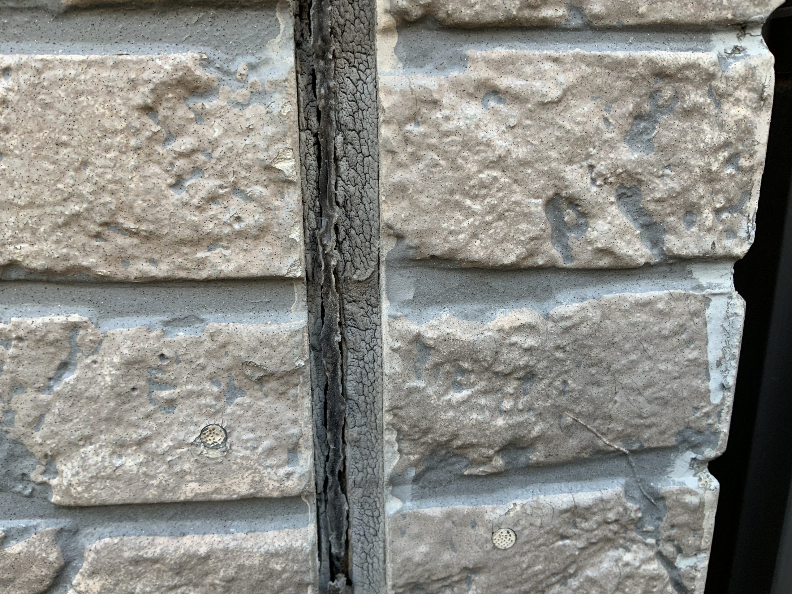 シーリングがひび割れた石目調の外壁