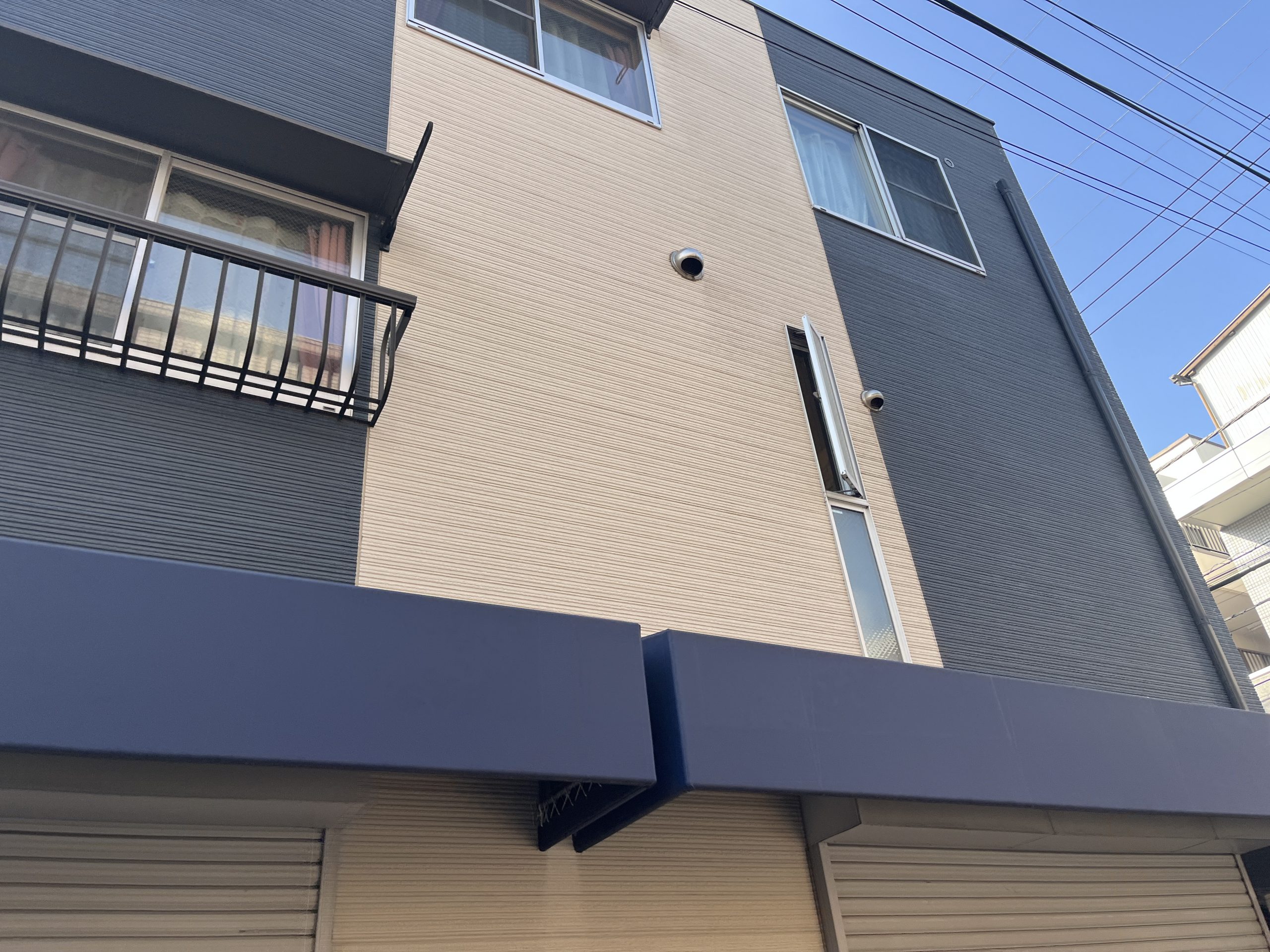 1階が商店のネイビーと茶色の外壁の建物