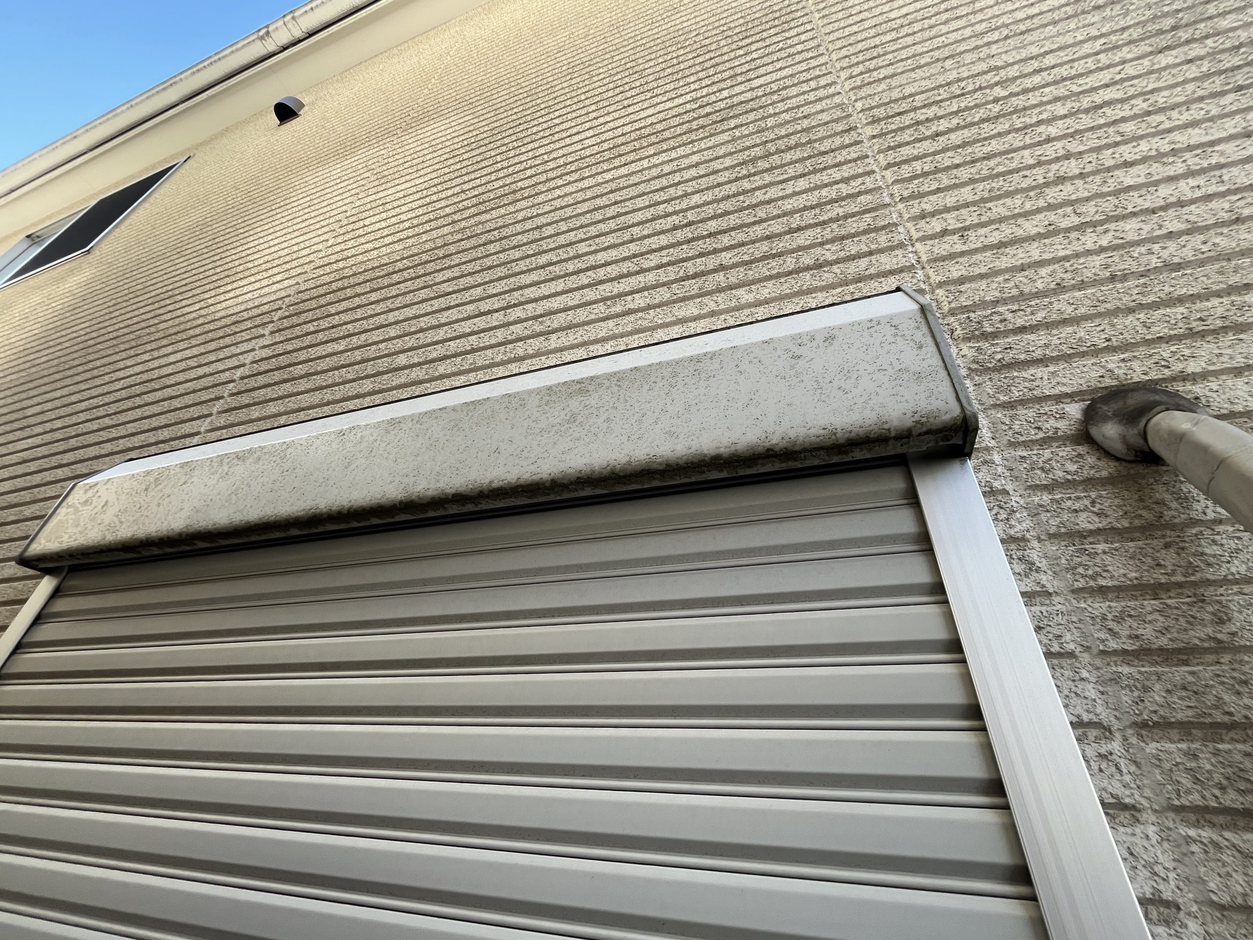 汚れが蓄積したベージュの外壁と白いサッシ