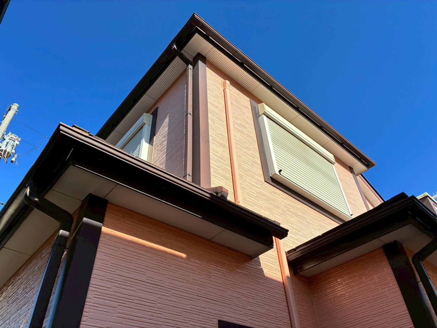 ピンクの外壁の住宅を見上げる