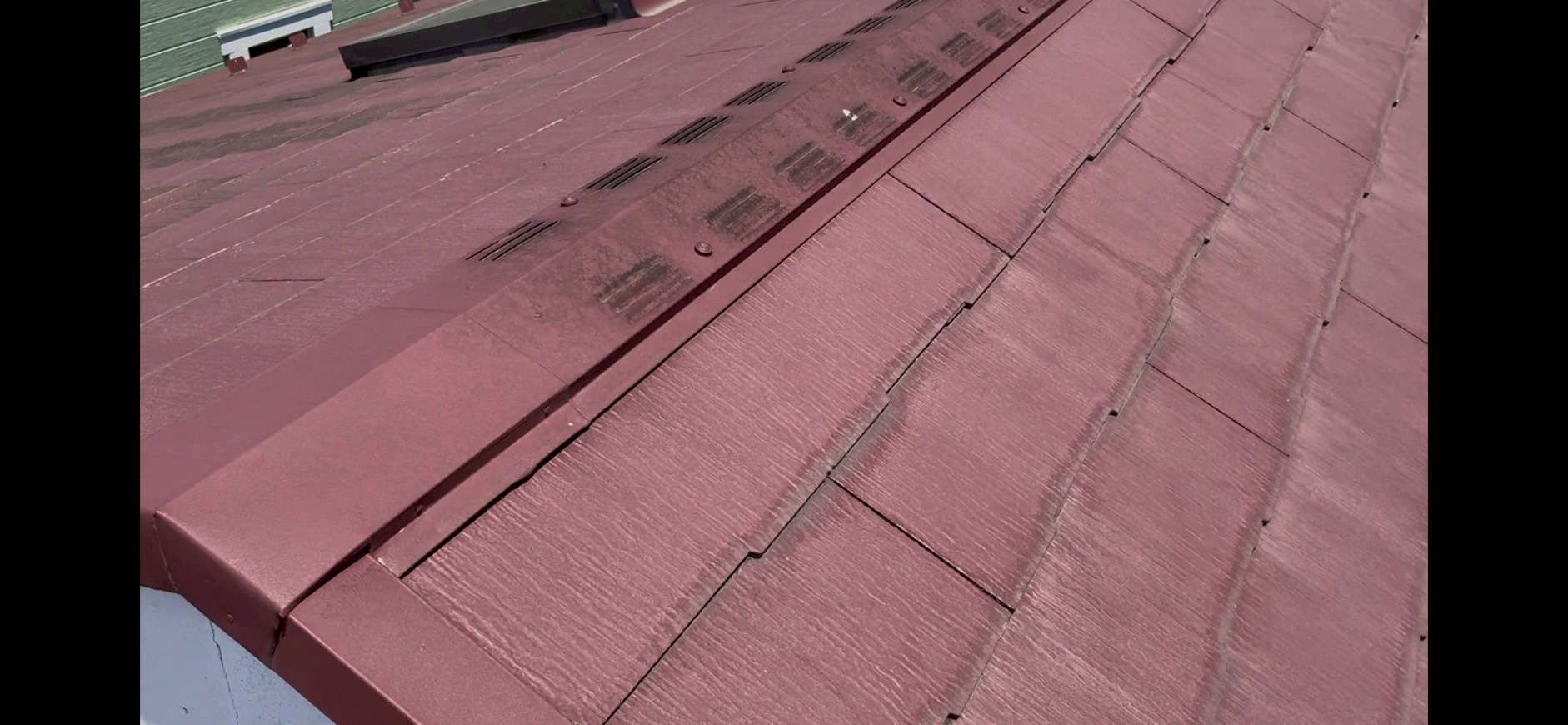 棟板金付近が苔で黒ずんでいる赤い屋根