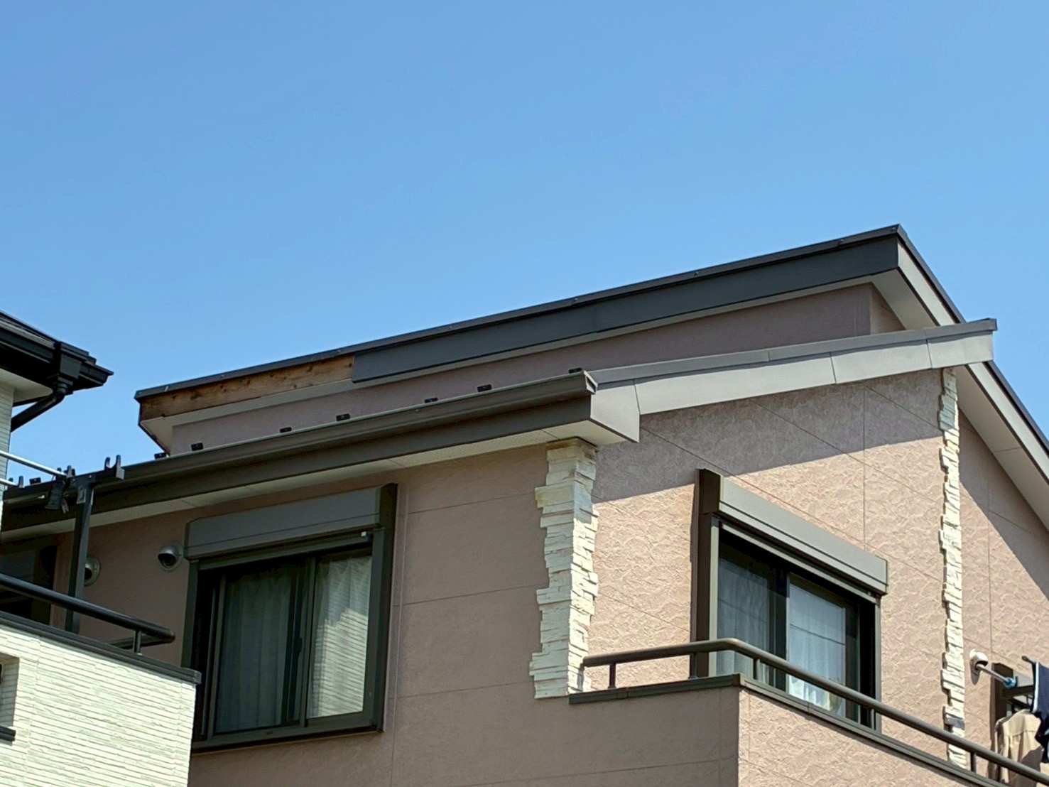 棟板金が強風で外れた薄いピンクの外壁の建物