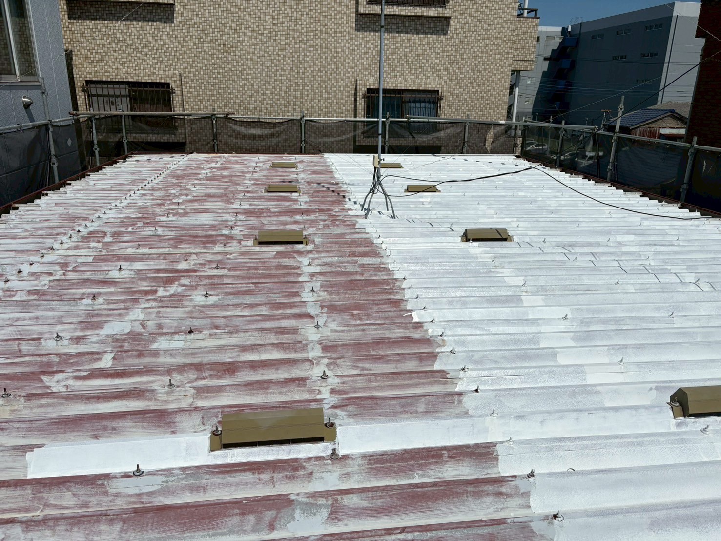 折半屋根に下塗り材を塗装中