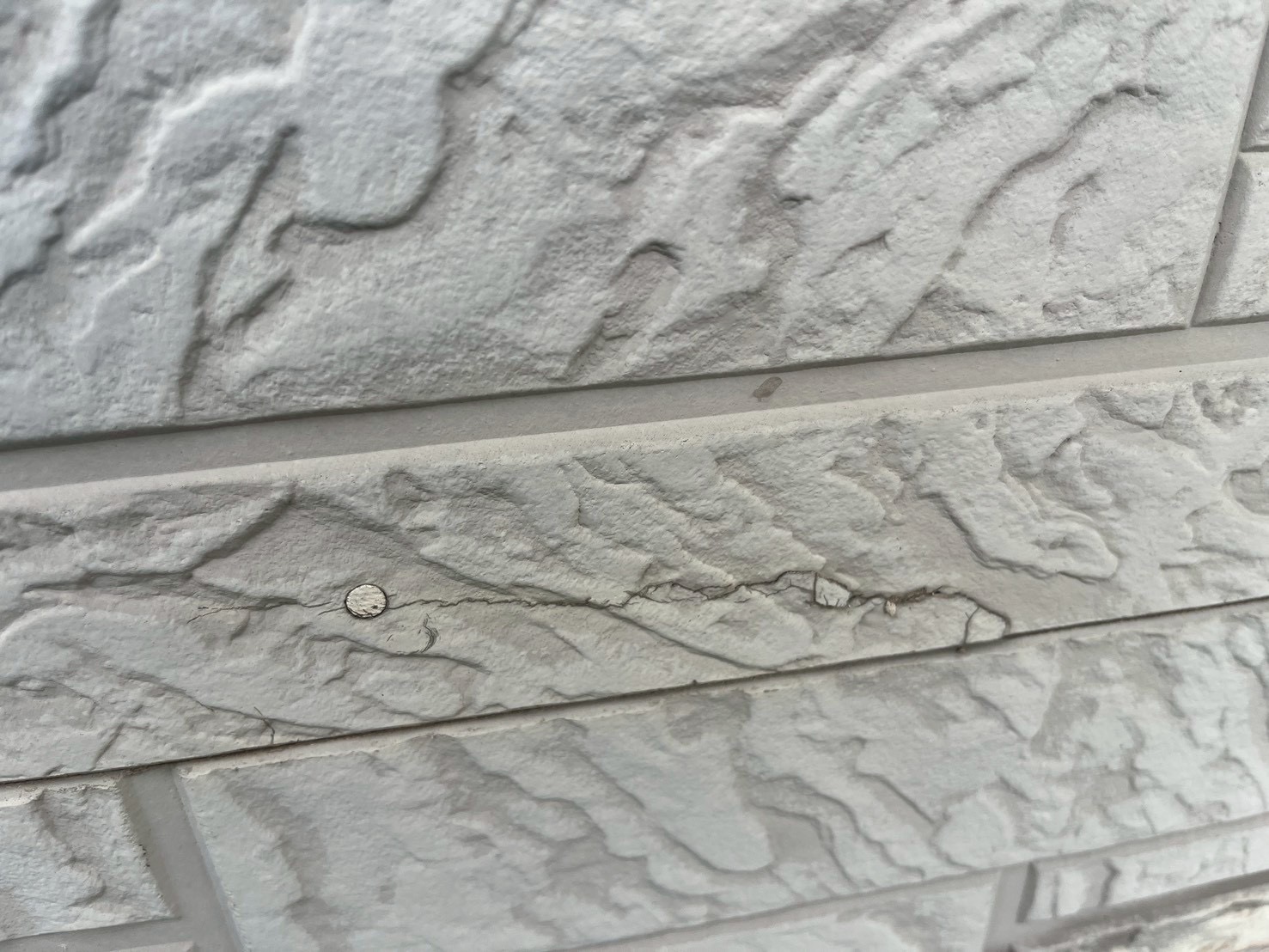 釘打ち箇所がひび割れている白い外壁