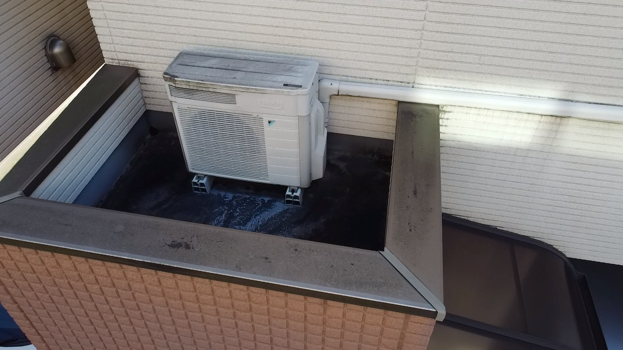 白と茶色の外壁とエアコン室外機