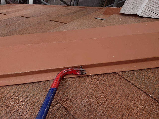 バールで棟板金の釘を取り外す様子