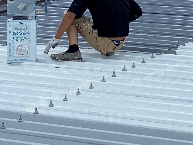 折板屋根にプレミアムルーフを塗布する職人