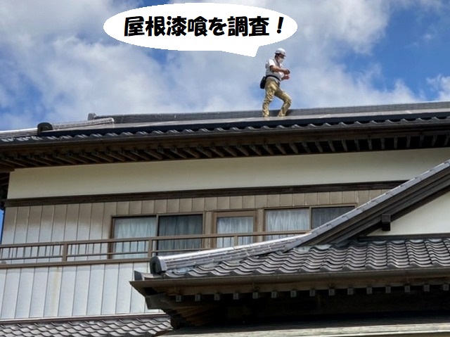 屋根に登り屋根漆喰の調査を行うスタッフ