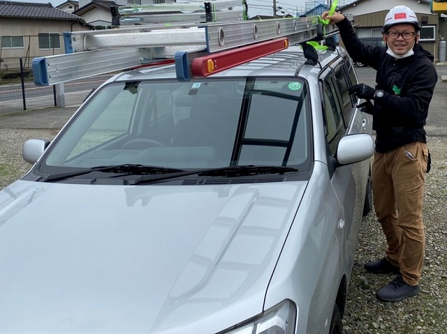 社用車から二連梯子を降ろす準備をするスタッフ