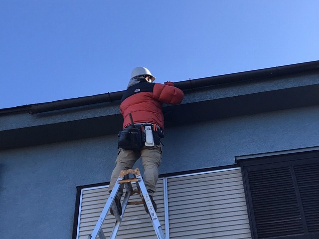 脚立に乗り、軒樋を取り付けている職人